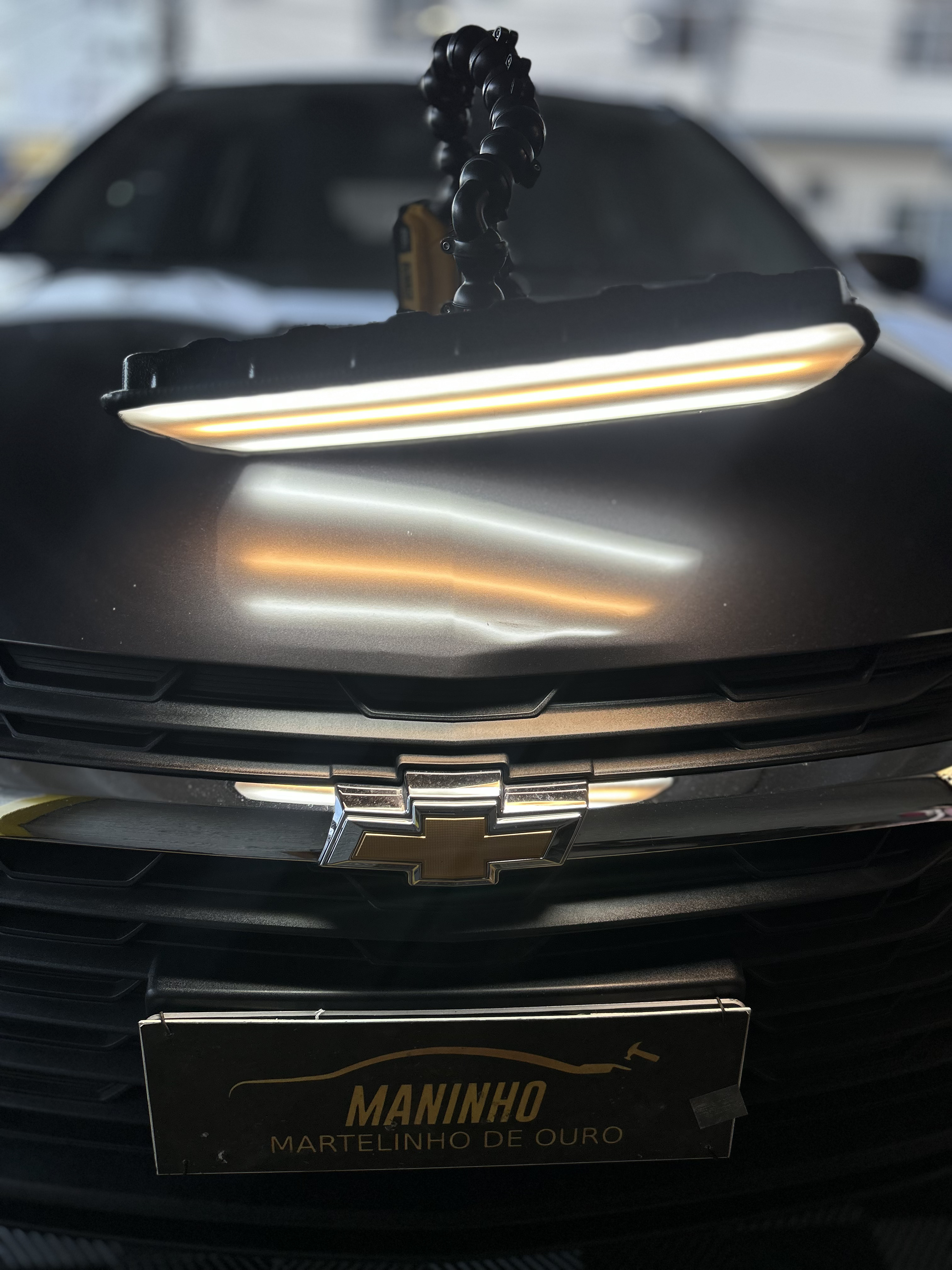 Capô de Chevrolet preto com amassado sob luz de inspeção